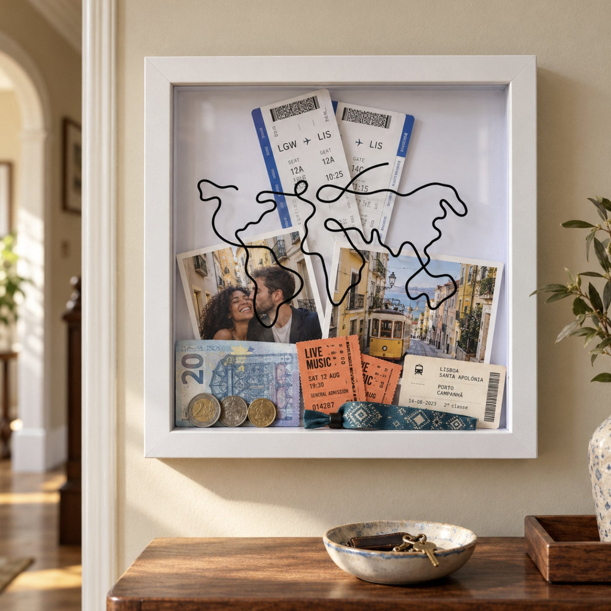 White Wandersake Memory Box hanging in a hallway above a sideboard, filled with Lisbon tickets, a couple's photo, a tram photo, gig tickets and coins